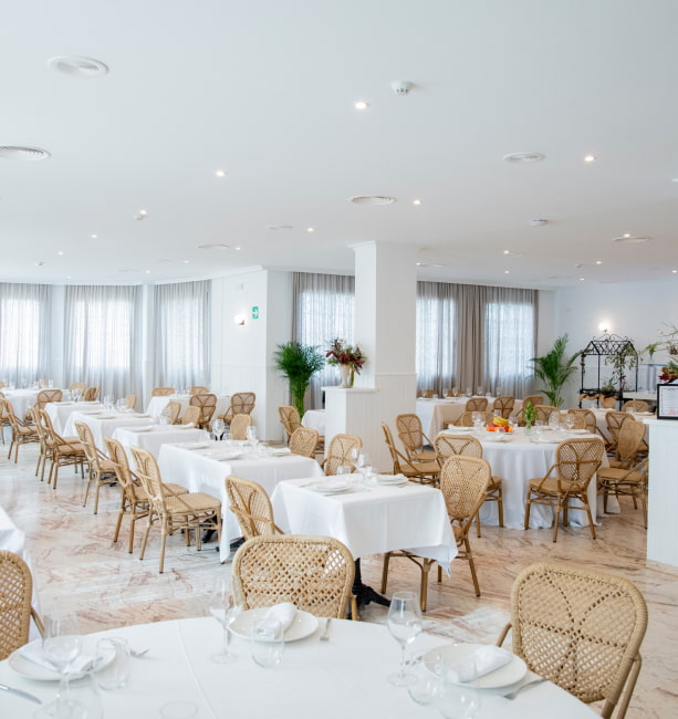 Restaurante La Vega Salón interior del restaurante, con manteles blancos y sillas de mimbre
